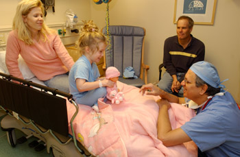 First surgical patient Olivia Follis, 4, chats with chief pediatric anesthesiologist Dr. Jay Deshpande before being taken into surgery as her parents look on. 