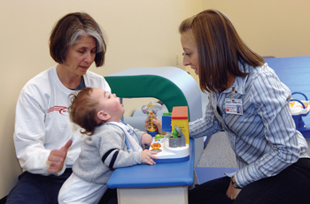 Physical therapist Heidi Kessler, left, and physical therapy student Kimberly Morgan work with patient Ryan Braswell, 1, in the Crawler Gym. (photo by Dana Johnson)