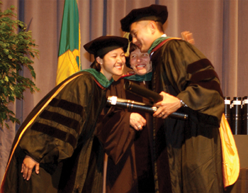 Dr. Joy Duong, class of 2002, and her brother David Duong, right, hug Dr. Bonnie Miller after Joy presented David with his diploma.