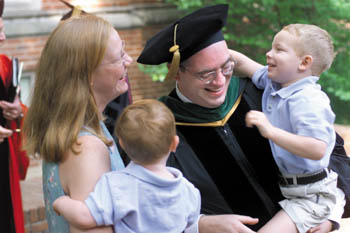 Medical school graduate Jim Saccomando laughs as his son Jimmy plays with his hat before the graduation ceremony began.  His wife Kim and other son Joey look on. (photo by Dana Johnson)
