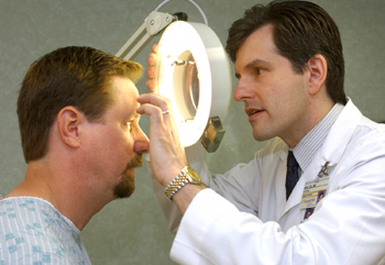 Dr. John Zic takes a closer look at Steven Steele's face during the annual skin cancer screening for Vanderbilt faculty and staff. Almost 200 people were screened at the Dermatology clinic on Wednesday morning. (photo by Dana Johnson)