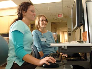 Spring Morse, R.N., right, walks Sara Angelly through the Dashboard information system in the Medical Intensive Care Unit.  
Photo by Anne Rayner