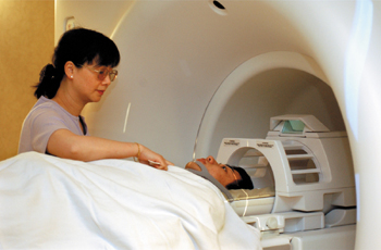 Gina Shyong, a functional MRI technician, sets up a subject for a brain scan. Functional MRI allows investigators to probe the working human brain. (photo by Dana Johnson)