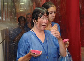 Mock patient Whit Crawford, foreground, and other volunteers scrub up in the decontamination shower during this week’s disaster drill.
