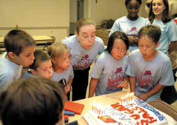 Dr. Jennifer Najjar gets help blowing out the candles on the 20th anniversary celebration cake last week.