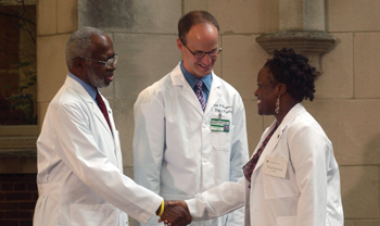 George Hill, Ph.D., left, and Scott Rodgers, M.D., congratulate Tera Howard on receiving her white coat.
Photo by Susan Urmy