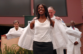 Nneamaka Agochukwu receives her white coat from VUSM Dean Steven Gabbe, M.D., as George Hill, Ph.D., right, and John Zic, M.D., look on. (photo by Dana Johnson)