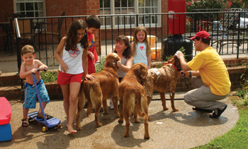 The Guy family of six makes family time a priority. From left, Spencer, 2, Danielle, 11, Christian, 9, mom Deanna Aftab Guy and Madeline, 5, help Jeff Guy bathe their three golden retrievers on a hot Sunday afternoon.
photo by Dana Johnson