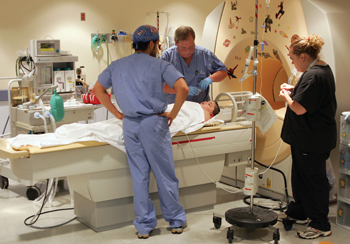Christopher Lemelle, M.D., left, Robert Atwood, C.R.N.A., and CT tech Shilon Burns prepare Trevor for his MRI. (photo by Neil Brake)
