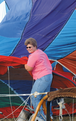 Carol Rhodes laughs as the fan nearly knocks her down as they inflate their hot air balloon.