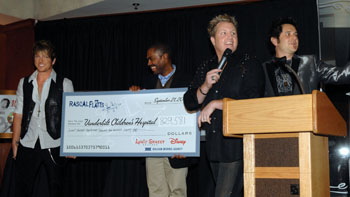 Joe Don Rooney, Gary LeVox and Jay DeMarcus of Rascal Flatts are all smiles after presenting a check of $829,581 to Kevin Churchwell, M.D., center, for Children's Hospital. (photo by Dana Johnson)