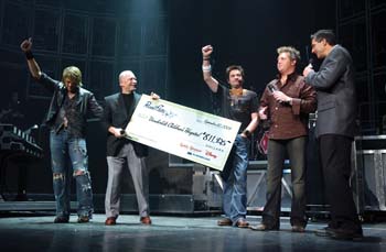 Rascal Flatts members present Harry Jacobson, M.D., second from left, and Jim Shmerling, right, with their donation at the group’s concert last Friday night at the Gaylord Entertainment Center. 
Photo by Dana Johnson